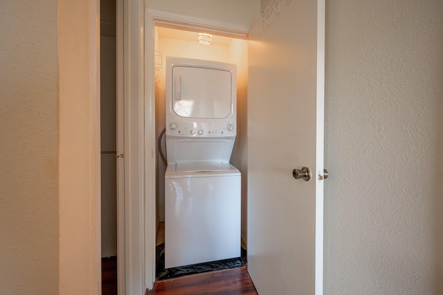 laundry room with dark hardwood / wood-style flooring and stacked washer / dryer