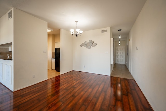 empty room with hardwood / wood-style floors and an inviting chandelier