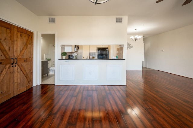 kitchen with pendant lighting, ceiling fan with notable chandelier, dark hardwood / wood-style floors, and black fridge