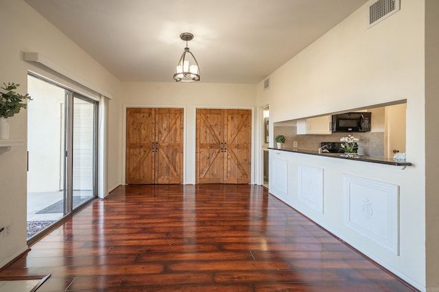 kitchen with a wealth of natural light, a chandelier, dark hardwood / wood-style floors, and decorative light fixtures