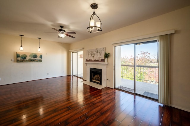 unfurnished living room featuring hardwood / wood-style floors, ceiling fan with notable chandelier, and a tiled fireplace