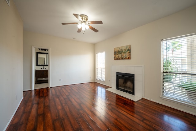 unfurnished living room with a tile fireplace, dark hardwood / wood-style flooring, a wealth of natural light, and ceiling fan