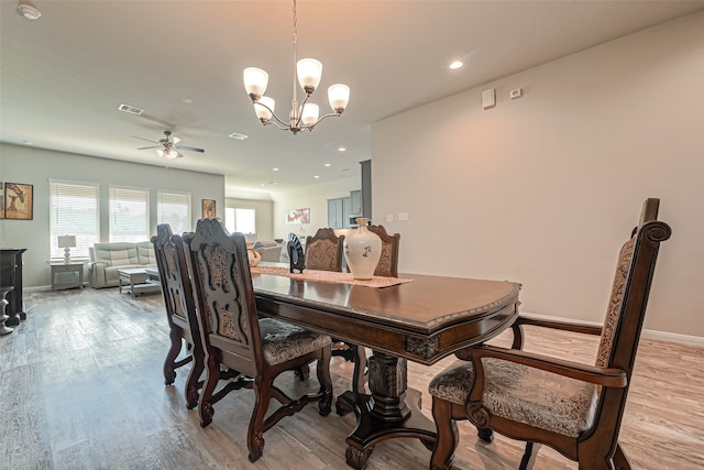 dining room with ceiling fan with notable chandelier and light wood-type flooring