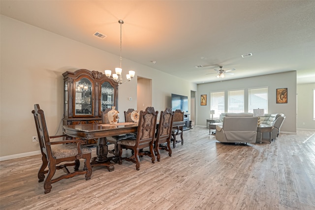 dining area with ceiling fan with notable chandelier and hardwood / wood-style floors