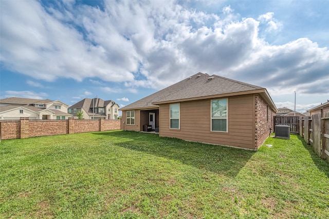 back of property with central AC and a lawn