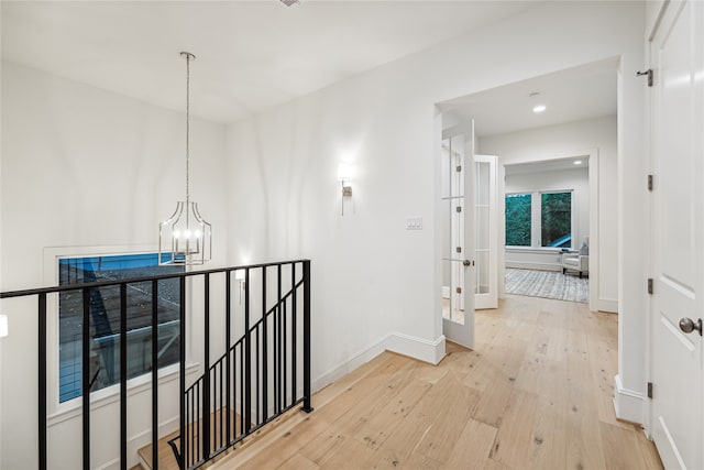 hall with a chandelier and light hardwood / wood-style floors