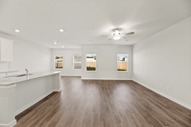 unfurnished living room featuring dark hardwood / wood-style flooring, ceiling fan, and sink