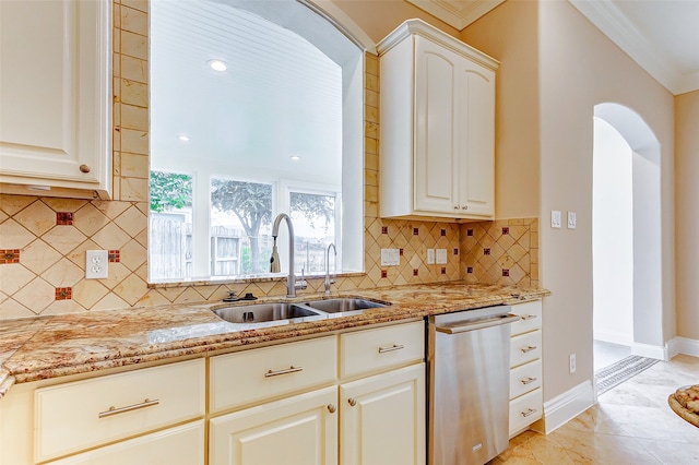 kitchen featuring light stone counters, stainless steel dishwasher, white cabinets, sink, and backsplash