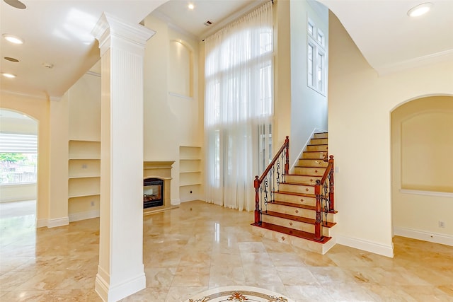 interior space with crown molding and decorative columns