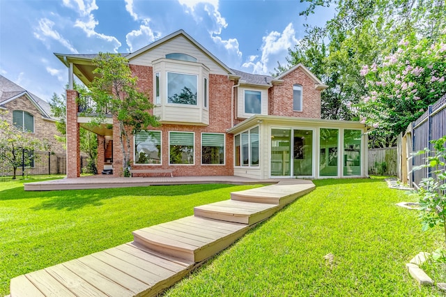 rear view of house featuring a sunroom, a patio, and a lawn