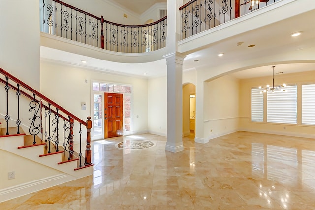 entrance foyer featuring ornate columns, ornamental molding, a high ceiling, and a notable chandelier