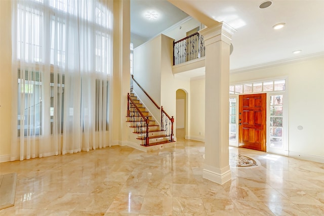 foyer entrance with ornate columns, crown molding, and a wealth of natural light