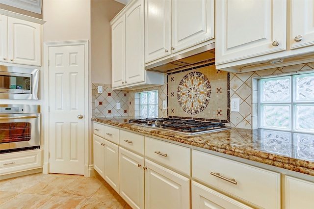 kitchen with light stone counters, plenty of natural light, stainless steel appliances, and tasteful backsplash