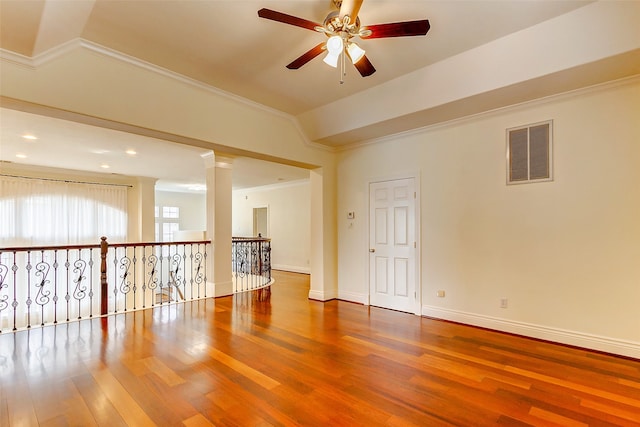 unfurnished room with ornate columns, crown molding, hardwood / wood-style floors, and ceiling fan