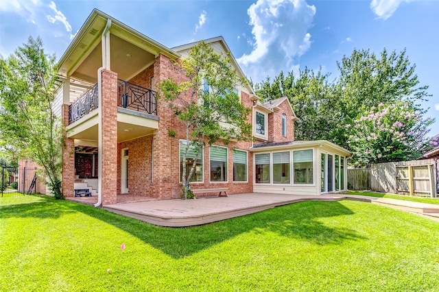 rear view of property featuring a patio, a yard, and a balcony