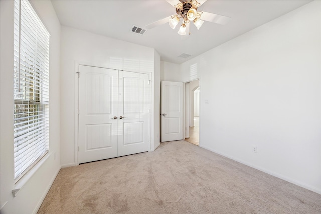 unfurnished bedroom featuring light carpet, a closet, and ceiling fan