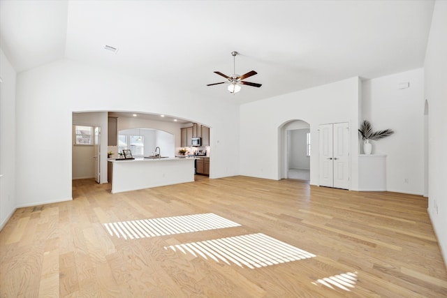 unfurnished living room featuring lofted ceiling, sink, light wood-type flooring, and ceiling fan