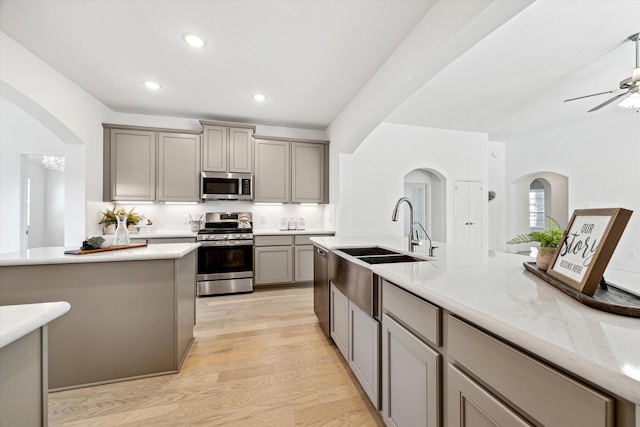 kitchen with light hardwood / wood-style floors, gray cabinets, sink, backsplash, and appliances with stainless steel finishes