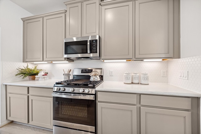 kitchen featuring gray cabinets, appliances with stainless steel finishes, backsplash, and light hardwood / wood-style floors