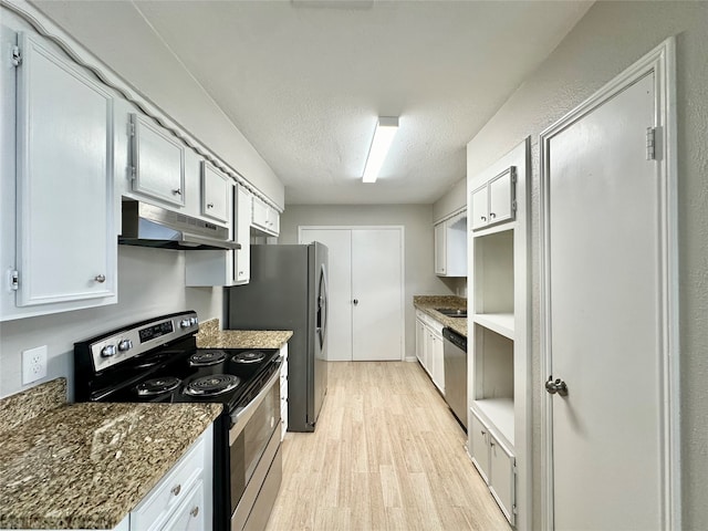 kitchen with a textured ceiling, white cabinetry, stainless steel appliances, dark stone countertops, and light hardwood / wood-style floors