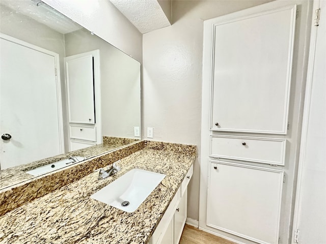 bathroom featuring hardwood / wood-style flooring, vanity, and a textured ceiling