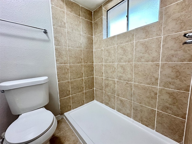 bathroom with tiled shower and toilet