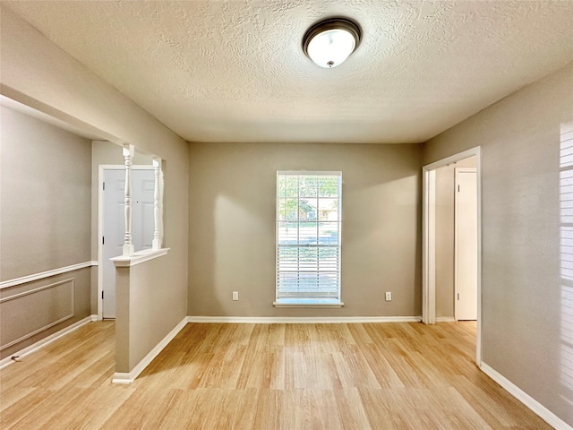 empty room featuring light wood-type flooring and a textured ceiling