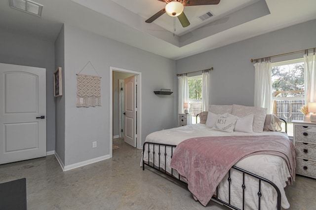 bedroom featuring multiple windows, ceiling fan, and a tray ceiling