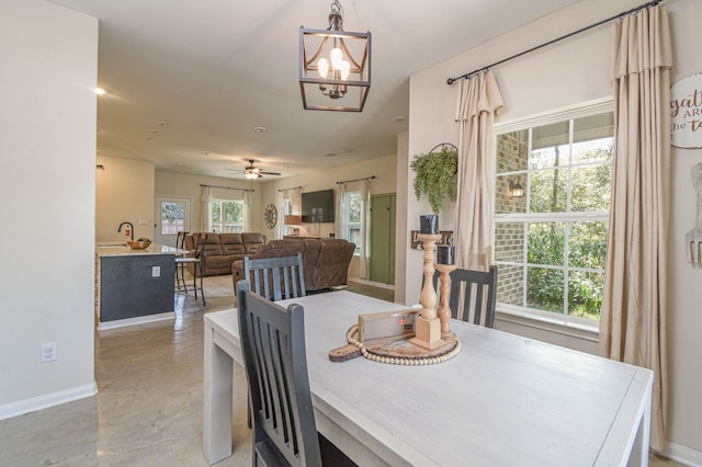 dining area with ceiling fan with notable chandelier and sink