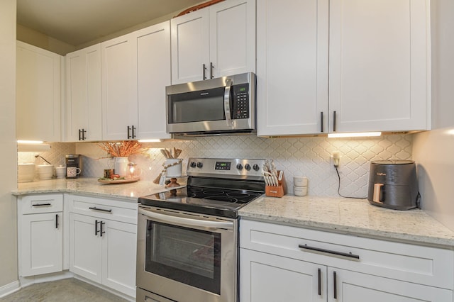 kitchen featuring stainless steel appliances, white cabinets, and tasteful backsplash