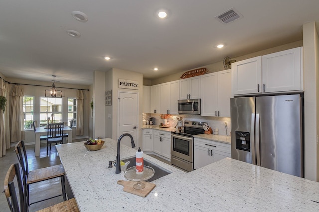 kitchen featuring light stone counters, appliances with stainless steel finishes, decorative backsplash, and white cabinetry