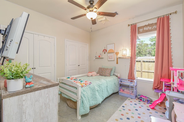 bedroom with light carpet, ceiling fan, and two closets