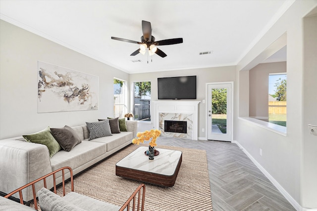 living room featuring a fireplace, a wealth of natural light, light parquet floors, and crown molding