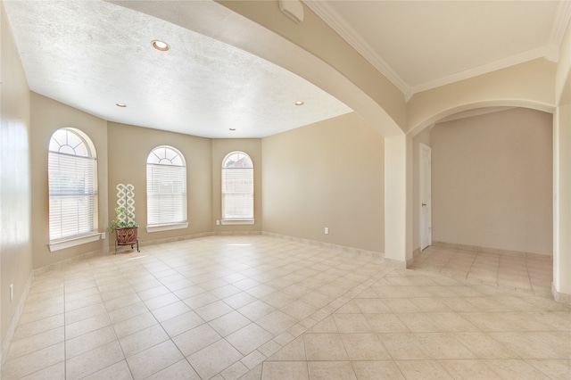 spare room featuring light tile patterned flooring, ornamental molding, and a textured ceiling