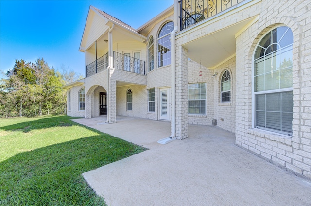 back of house featuring a patio, a balcony, and a lawn