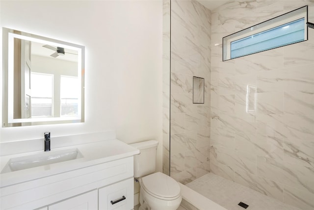 bathroom with tiled shower, vanity, and toilet