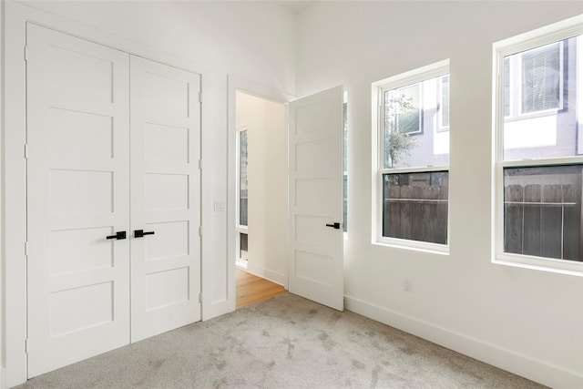 unfurnished bedroom with light carpet and a closet