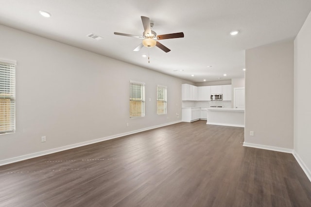 unfurnished living room featuring ceiling fan and dark hardwood / wood-style flooring