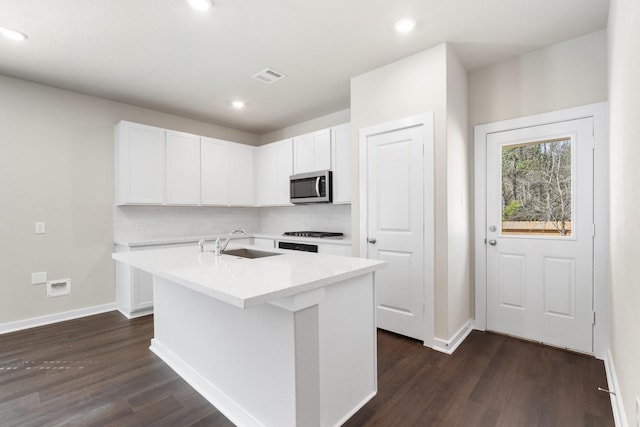 kitchen featuring a center island with sink, tasteful backsplash, white cabinets, sink, and dark hardwood / wood-style floors