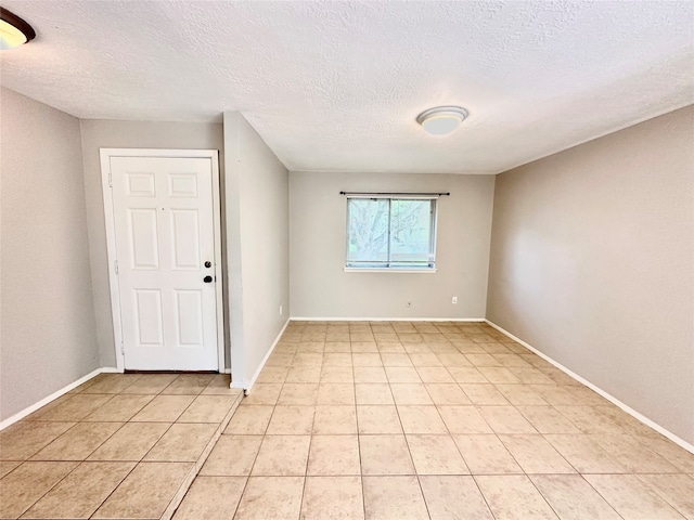 tiled empty room featuring a textured ceiling