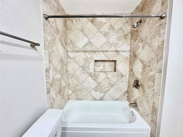 bathroom featuring a textured ceiling, tiled shower / bath combo, and toilet