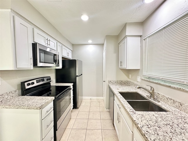 kitchen featuring light tile patterned flooring, appliances with stainless steel finishes, sink, and white cabinetry