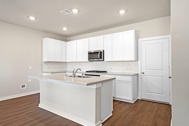 kitchen featuring tasteful backsplash, visible vents, stainless steel microwave, and dark wood finished floors