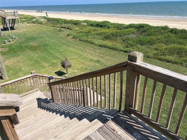 deck with a beach view, a lawn, and a water view