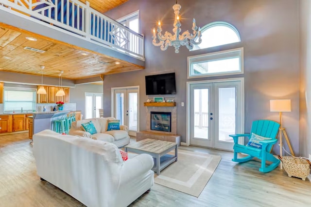 living room with a towering ceiling, french doors, wood ceiling, and light hardwood / wood-style flooring