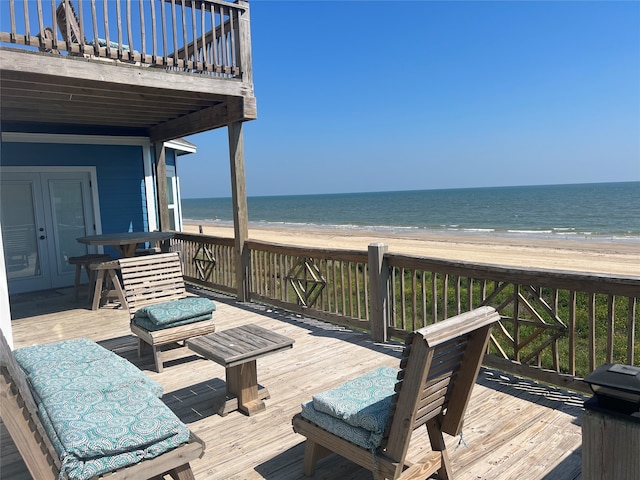 wooden deck featuring a water view and a beach view