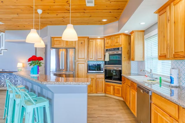 kitchen with sink, decorative light fixtures, light hardwood / wood-style flooring, stainless steel appliances, and a kitchen breakfast bar