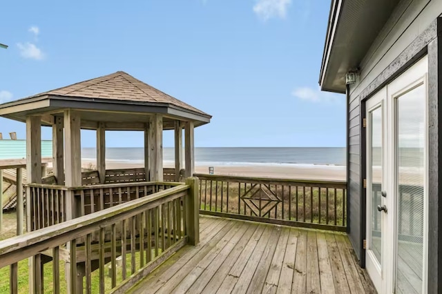 wooden terrace with a gazebo, a water view, and a beach view