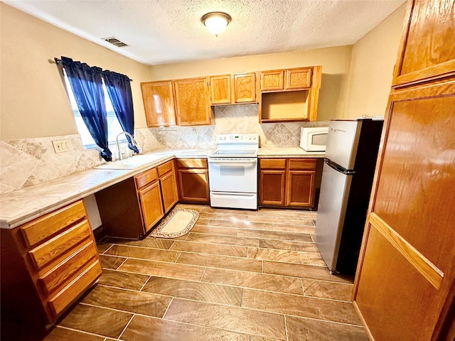 kitchen with tasteful backsplash, white appliances, sink, and a textured ceiling