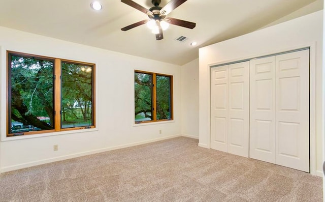 unfurnished bedroom featuring a closet, light carpet, vaulted ceiling, and ceiling fan